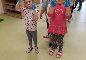 Dziewczynki pokazują pomalowane na niebiesko rączki